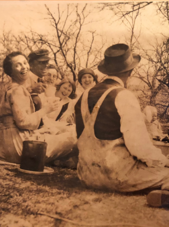 Sepia photo of people in early 20th century dress having a picnic
