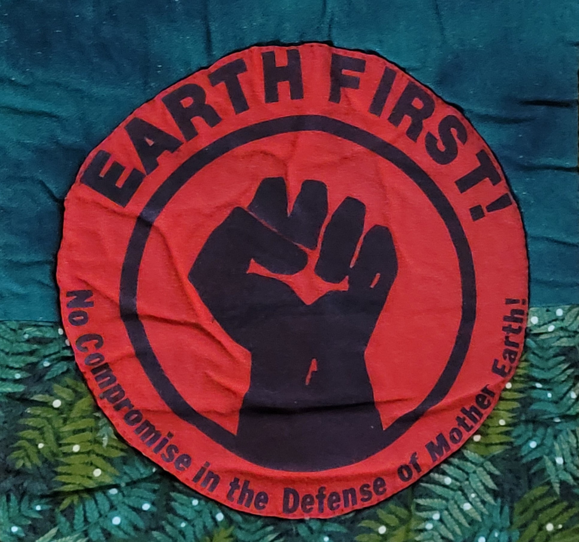 Quilt square of the Earth First Logo featuring a clenched fist and the phrase