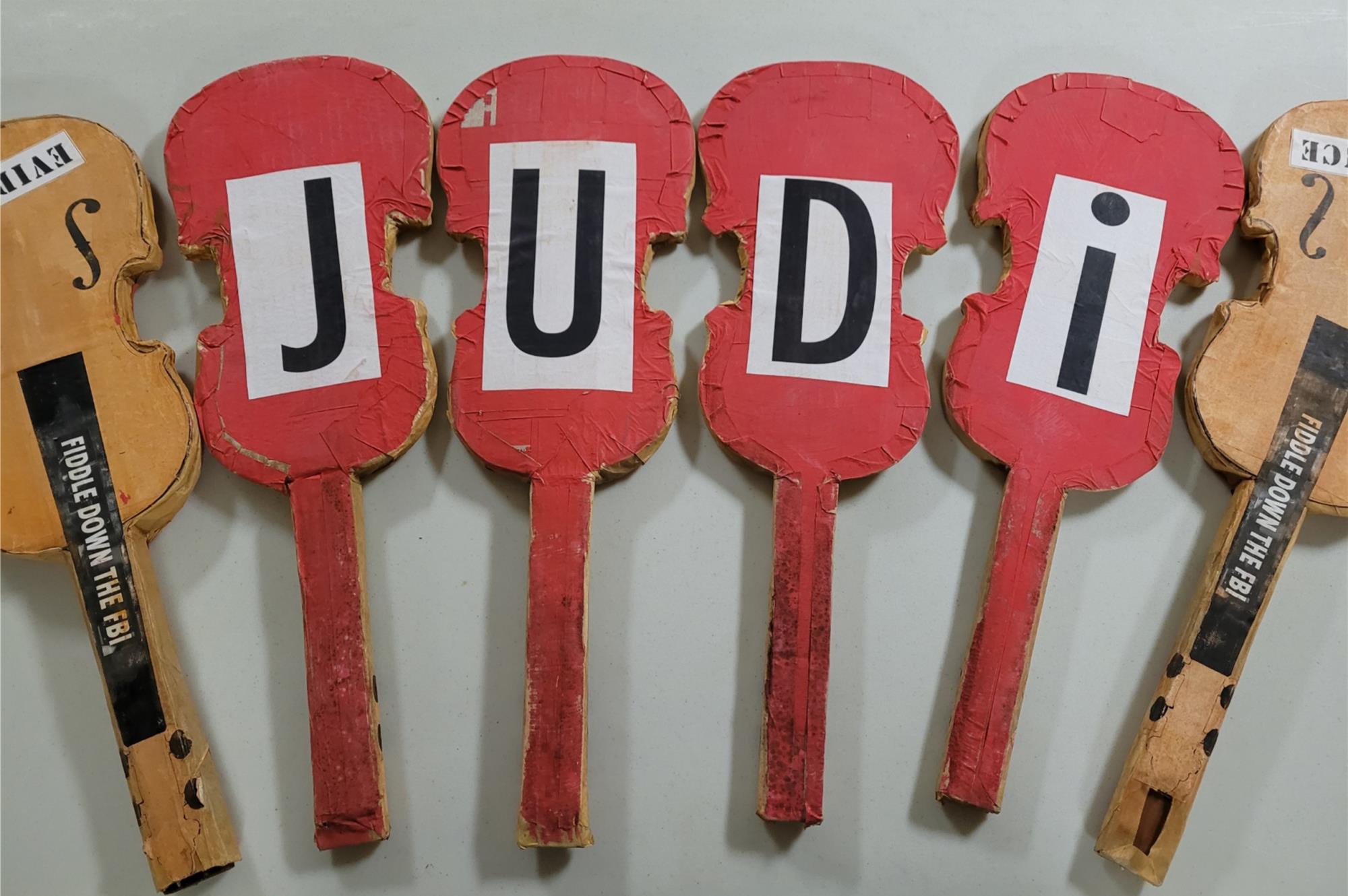 Fiddles arranged in a row with letters spelling "Judi"