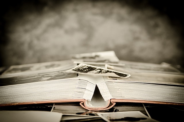 Sepia photo of open photo album, view is from the side, detail of photos is not visible.